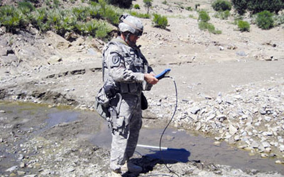 Lt. Col. Kevin Sari uses a hydrometer to test the velocity and chemical makeup of a tributary that feeds into the Shamal River in Afghanistan.