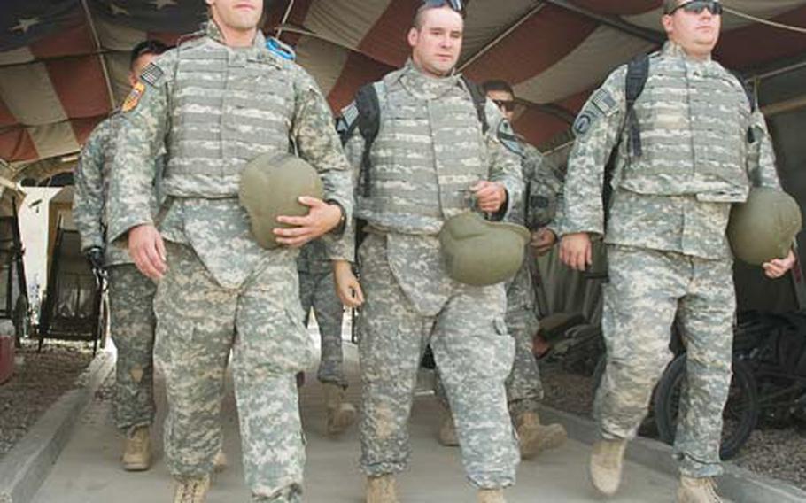 From left: Sgt. Robert Brown, retired Staff Sgt. Bradley Gruetzner and Sgt. Christopher A. Burrell walk through “Hero’s Highway” on June 25 at the Air Force Theater Hospital at Joint Base Balad, Iraq. Brown, Gruetzner, Burrell and four other soldiers wounded in Iraq had the opportunity to return to the places they once served in a program called Operation Proper Exit.