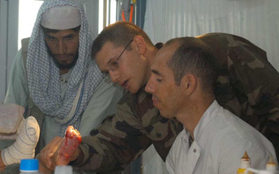 Maj. Julien, center, inspects Shahram’s left foot. His father and Mickael, a French marine corporal and paramedic, look on.