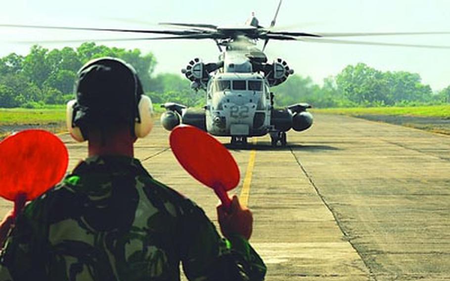 A member of the Indonesian military directs a U.S. CH-53E Super Stallion helicopter across the runway at Tabing Airfield in Padang, Indonesia, on Tuesday.