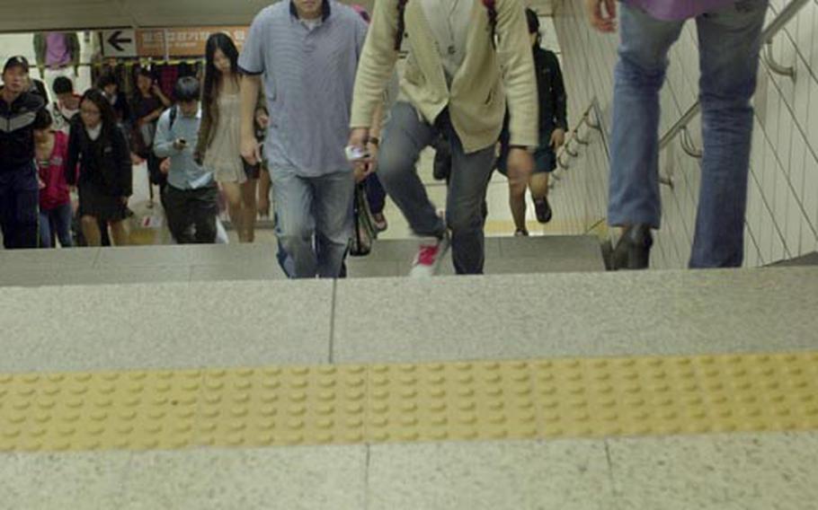 Seoul government officials say it is going to take some time for South Koreans to get in the habit of keeping to the right, as seen at the Itaewon subway station. On Oct. 1, Seoul began a campaign to get everyone to walk on the right. Signs are taped to the floor at the subway station as part of the campaign.