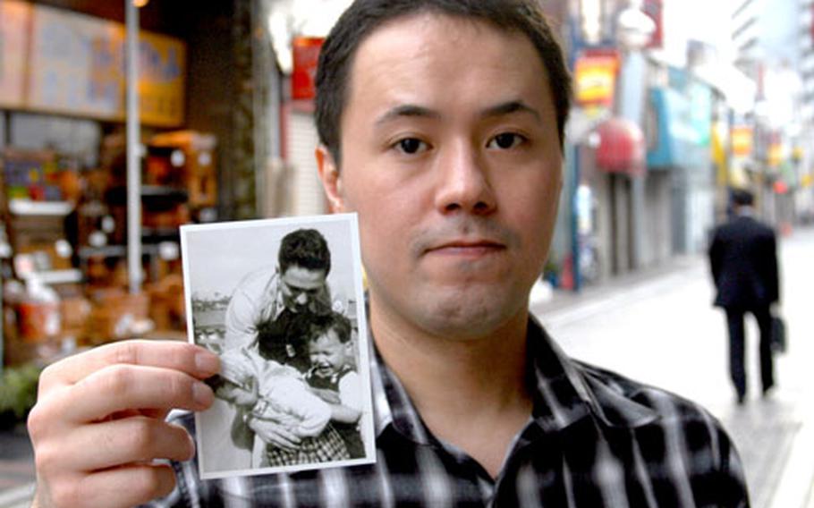 Masami Nakamura, 33, holds a picture of the grandfather he knows only as "George" holding his young mother and an unidentified child in the late 1940s in Japan. Nakamura is using DNA testing, Web sites and the U.S. government to try to find out more about his grandfather, whom he believes died in the Korean War.