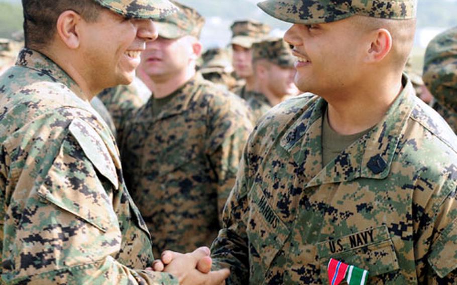 Hospital Corpsman 2nd Class William J. Harris is congratulated by a fellow servicemember after receiving two Bronze Star Medals, a Navy Commendation Medal and a meritorious promotion during a ceremony Monday at Marine Corps Air Station Futenma, Okinawa.