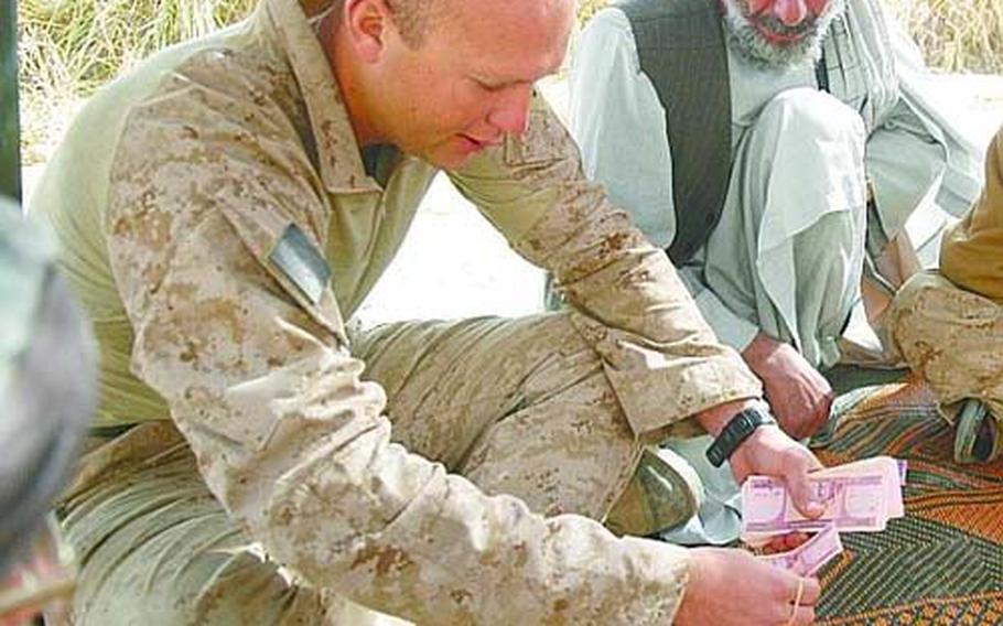 Capt. Steve Karabin, commander of 1st Battalion, 3rd Marine Regiment’s Company C, counts out Afghan dollars for a project to refurbish a health clinic in Nawa. As security improves, civil and military forces in Nawa are increasingly focused on community projects. But in Helmand province’s rural towns, the ability of the Afghans to properly staff health clinics, schools and other important institutions remains a challenge.