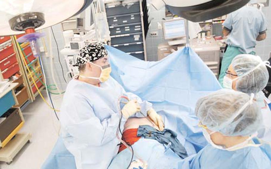 Dr. (Col.) George Broughton, assisted by Petty Officer 2nd Class Patricia Sanford and Lt. Cmdr. Flemming French, performs a male breast reduction on an active-duty patient at Landstuhl Regional Medical Center in Germany.