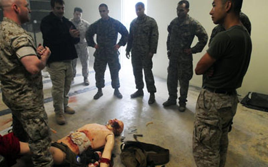Petty Officer 1st Class Jeremy Dunlap (left) and retired Navy Corpsman Mark Kane (second from left) briefs Marines and sailors from Special Operation Training Group after they finished treating a manikin during a medical simulation scenario.