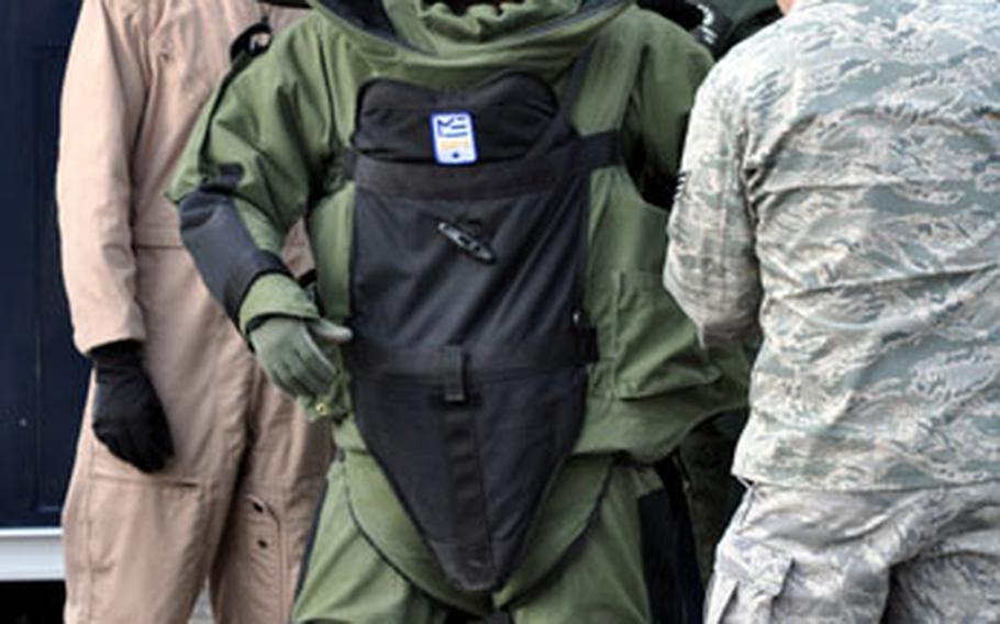 Fellow EOD technicians help Staff Sgt. Michael Overton into his bomb protection suit.