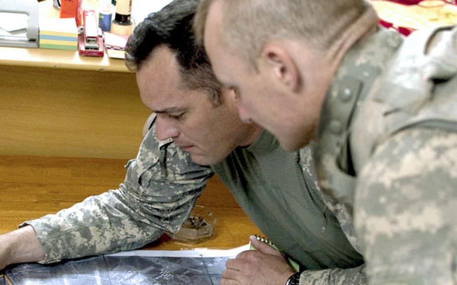 U.S. Army Capt. Scott Wares, left, and Staff Sgt. James Davis plan a route for a raid to be conducted with Iraqi police in the northern town of Hawijah.