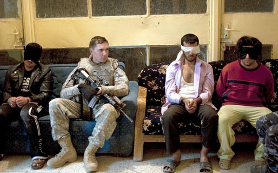 Men arrested during a joint raid in Hawijah sit in the lobby of the local police station. The man at far right, picked up after cutting off a police officer in traffic, was later released.