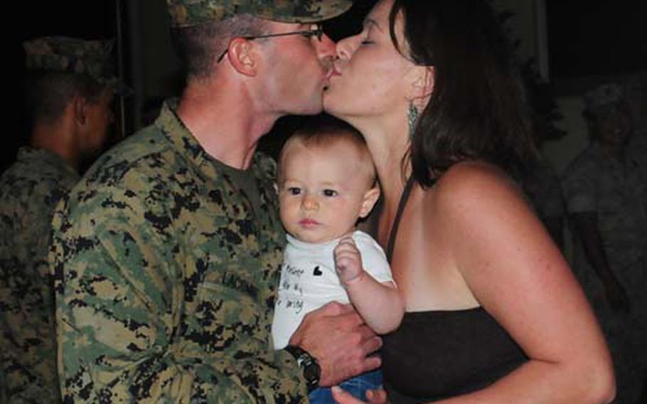 Sgt. Thomas Lacombe, a Marine from Currie, N.C., kisses his wife, Martha, after returning Wednesday to Camp Schwab, Okinawa, after a nine-month deployment in Afghanistan. Lacombe, 27, holds his son, Aaron, who was only 9 days old when the sergeant deployed.