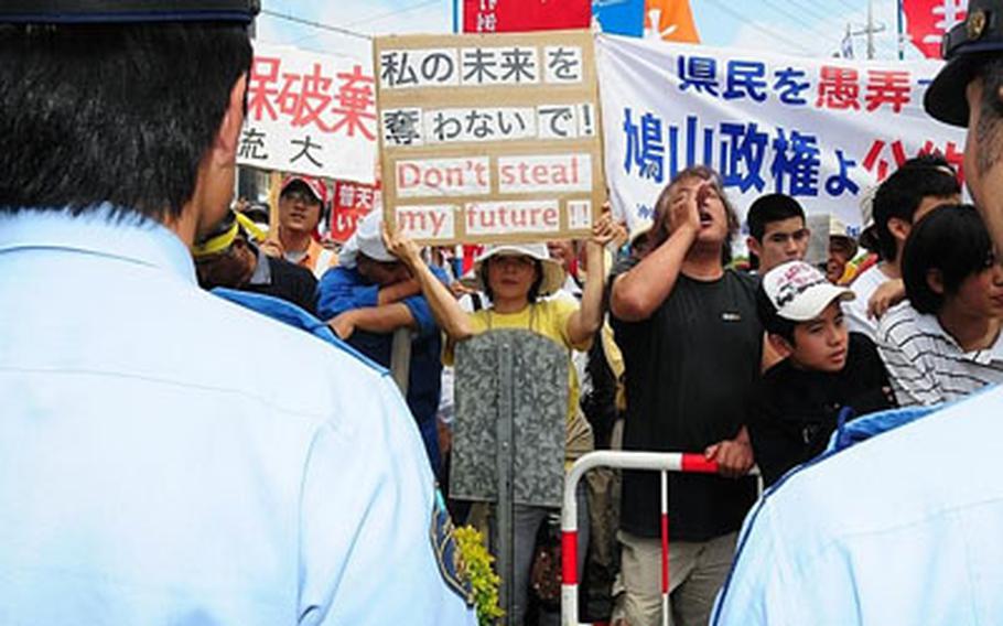 Demonstrators gather outside the Futenma Elementary School No. 2, chanting anti-military base slogans, while inside some protesters shouted "Shame! Shame!" to Prime Minister Yukio Hatoyama during a Town Hall meeting in which he declared that U.S. Marine units would not be transferred off Okinawa.