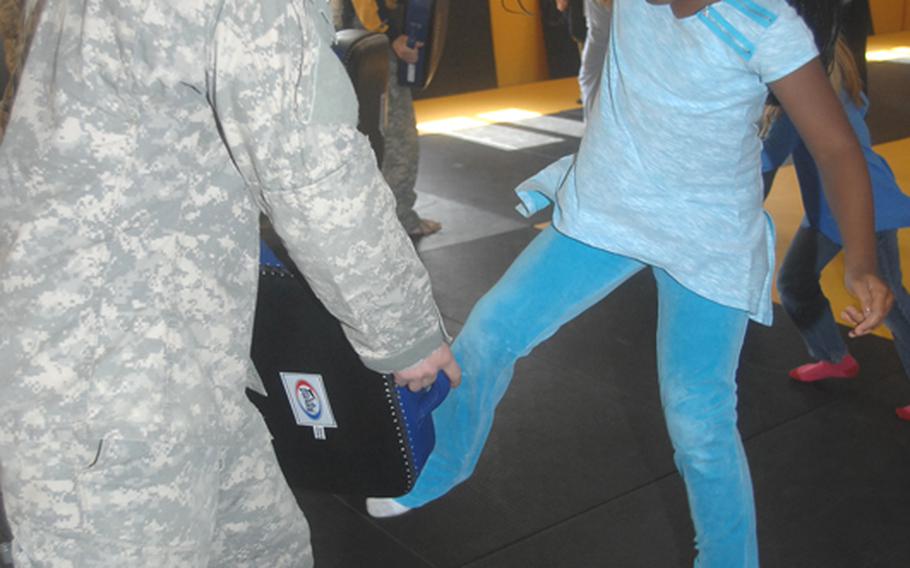 First Lt. Ian McCollum, 27, of Camarillo, Calif. holds a pad while Grafenw?hr Elementary School fourth-grader Zatajia McDaniel, 9, aims a kick during a martial-arts and self-defense demonstration at the 7th Army Noncommissioned Officer Academy on Friday.