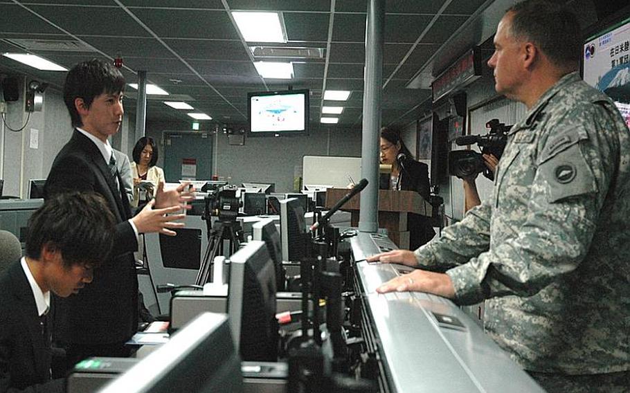 A Heisei International University student talks Friday with Maj. Gen. Francis Wiercinski, the U.S. Army?s commander in Japan, inside the Army's command and control room at Camp Zama. The students toured the base Friday as part of their thesis seminar about the U.S.-Japan alliance.