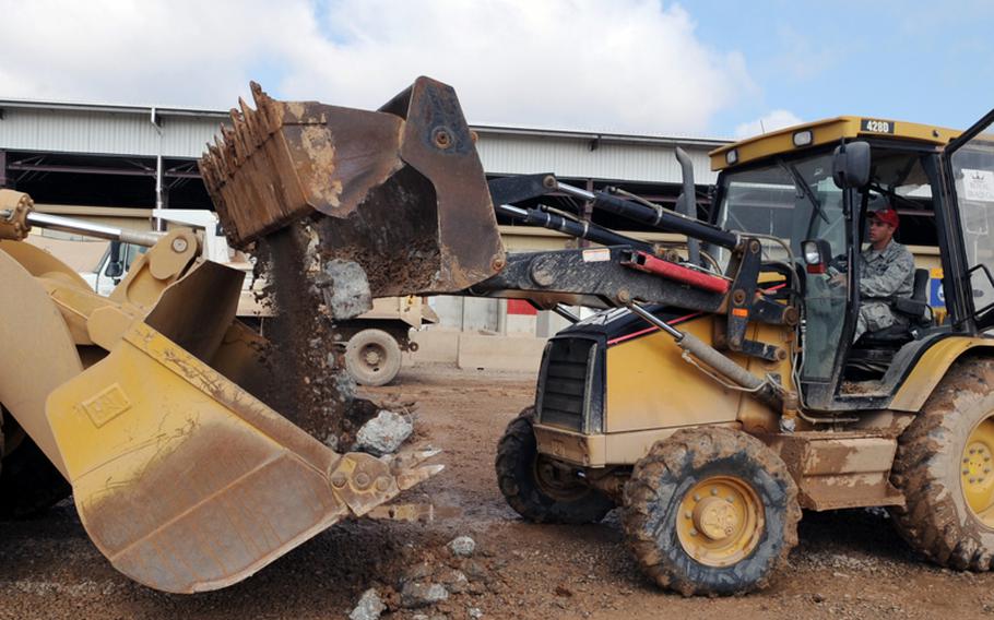 Airman Britton Busbee removes dirt and rocks from a parking lot during construction of the transient village at Joint Base Balad, Iraq, on March 2.