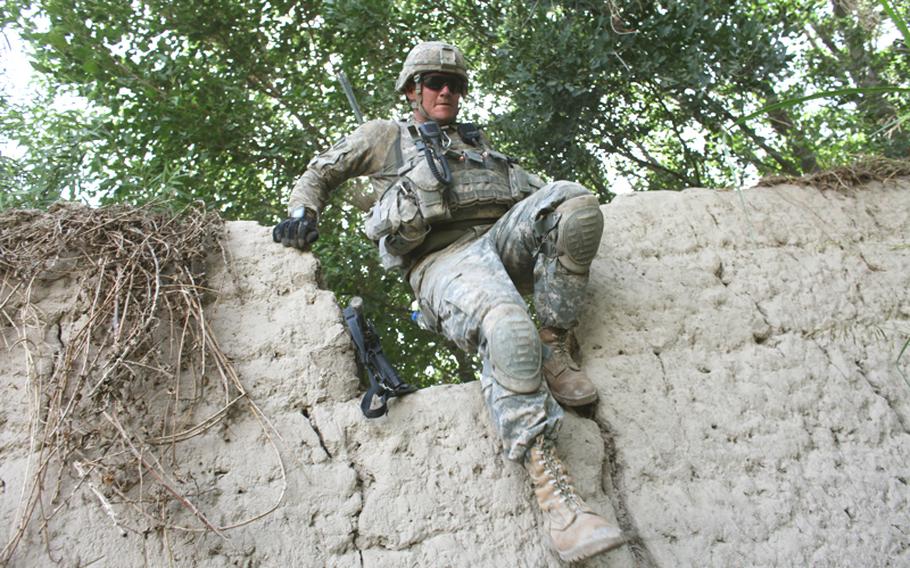 Pfc. Micah Kahn, 23, of Nashville, Tenn., with Company B, 2nd Battalion, 508th Parachute Infantry Regiment, scrambles through a break in a mud wall while on patrol to search for hidden Taliban bombs in the orchards surrounding the village of Deh-e-Kuchay in the Arghandab valley of Kandahar province, Afghanistan. May 26, 2010.