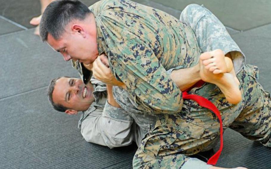 Capt. Jason Cyr, bottom, battles Marine Corps Capt. Chris Esrey during the Army Combatives tournament last year at Fort Benning, Ga. Combatives officials say they are considering awarding colored belts to designate soldiers' skill at its Combatives hand-to-hand fighting system.
Vince Little/U.S. Army