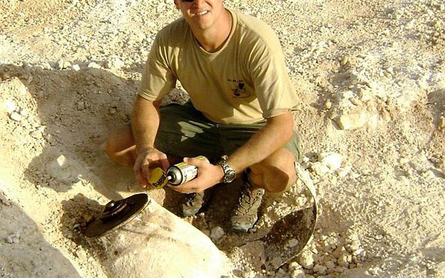 Petty Officer 1st Class Clifford Sabo, of Explosive Ordnance Disposal Detachment Marianas, squats next to the 1,000-pound bomb discovered Monday at a construction site on U. S. Naval Base Guam. The EOD team determined the bomb was stable. They will remove the fuse on Saturday in order to safely transport it for disposal at the Naval Base Guam Ordnance Annex. During the procedure, a portion of the base will be temporarily closed and personnel in housing, offices and barracks relocated.
