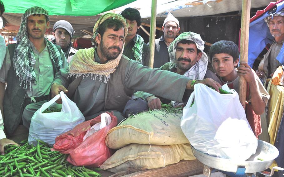 A vegetable vendor weighs a bag of green peppers in the Kabul Fruit Market on June 9. Vendors complain that they must pay bribes to government officials to stay in business.