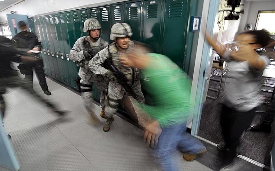 Master Sgt. Thomas Rood, center front, and Staff Sgt. Shane Brown rush role players acting as hostages out of a classroom during a drill in Edgren High School at Misawa Air Base, Japan, on Thursday.