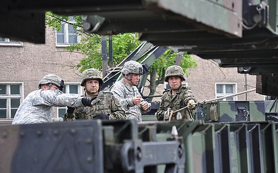 Soldiers from U.S. Army Europe's 5th Battalion, 7th Air Defense Artillery Regiment out of Kaiserslautern, Germany, familiarized members of the Polish military last month on how to load and unload Patriot missile canisters in Morag, Poland. From left to right: U.S. Army Spc. Steven R. Faddis, Polish air force Capt. Basuk Krzyszt, U.S. Army Spc. Anthony R. Doty, and Polish land force Capt. Bogdan Wludarczyk.