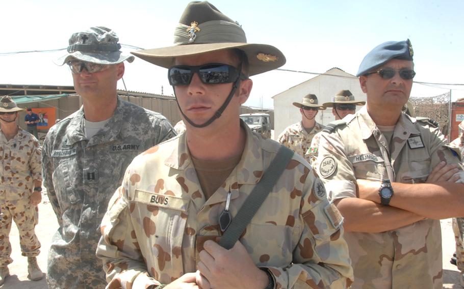 08/17/2010 - From left, U.S. Army chaplain (Capt.) James Breckenridge, Australian Army Craftsman Warren Buys and Dutch Army Capt. Marco Heijmans watch a ceremony commemorating Australian efforts in the Vietnam war at Multinational Base Tirin Kot this week.