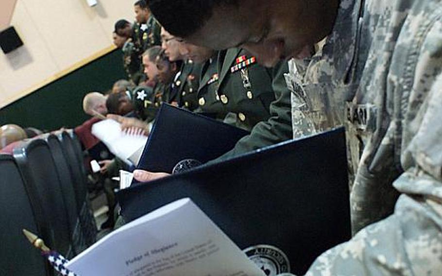 Spc. Ibrahim Kargbo, stationed at Camp Casey, South Korea, looks at his citizenship certificate during a naturalization ceremony Friday at Yongsan Garrison, South Korea. Fifty-five servicemembers and 17 spouses became U.S. citizens during the ceremony at Yongsan.