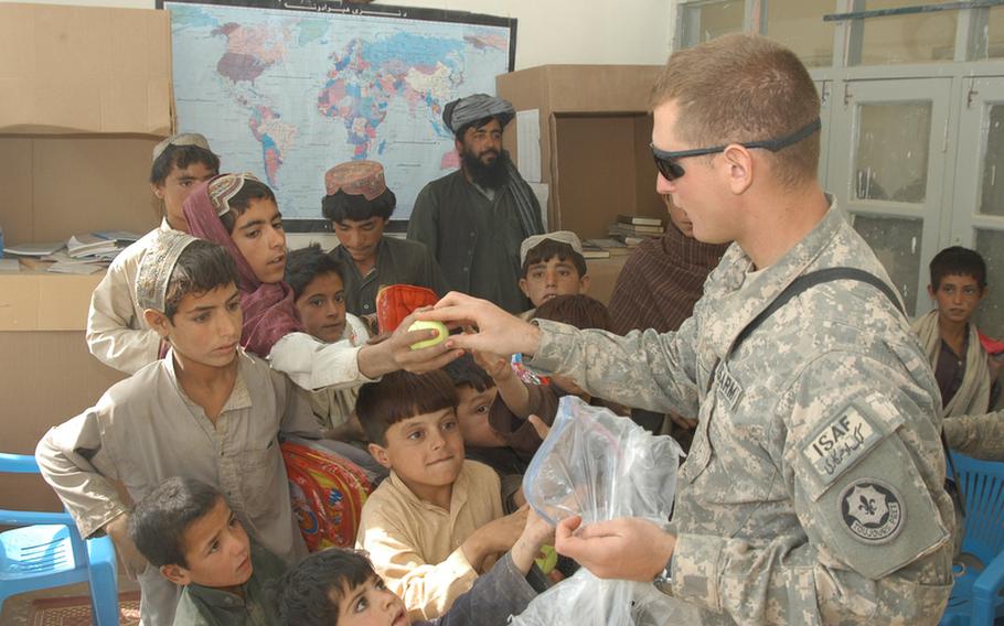 Second Lt. Loris Lepri, the 2nd Platoon leader for K Troop, 4th Squadron, 2nd Stryker Cavalry Regiment, hands out tennis balls at a school in Robat, Afghanistan, during a recent visit. Visiting soldiers also gave two soccer balls to headmaster Fazal Rehman, who is pictured standing in the back.