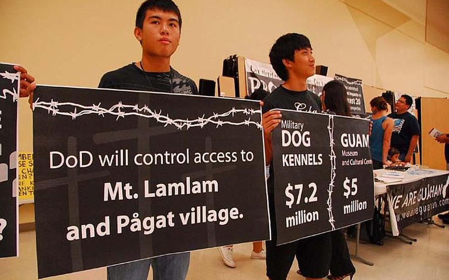 Members of the group We Are Guahan hold protest signs during a Navy-sponsored public meeting on plans to build firing ranges on Guam ancestral land.
