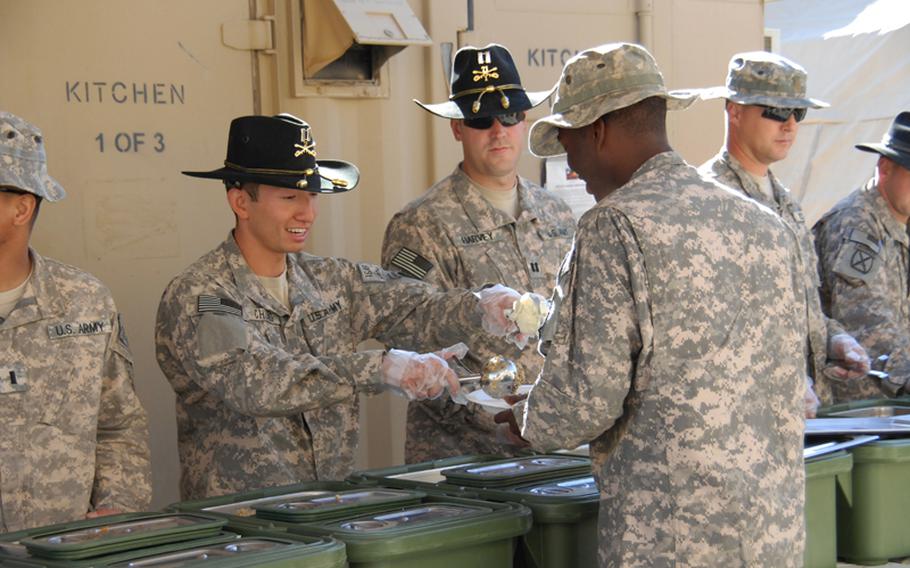 Capt. Woowon Chung dishes out stuffing and mashed potatoes at FOB Tarnek in the Dand district of Kandahar Thursday for troops with 1st Squadron, 71st Cavalry Regiment, 10th Mountain Division out of Ft. Drum. Some of the officers rocked their stetsons as they served the meal to the enlisted soldiers.