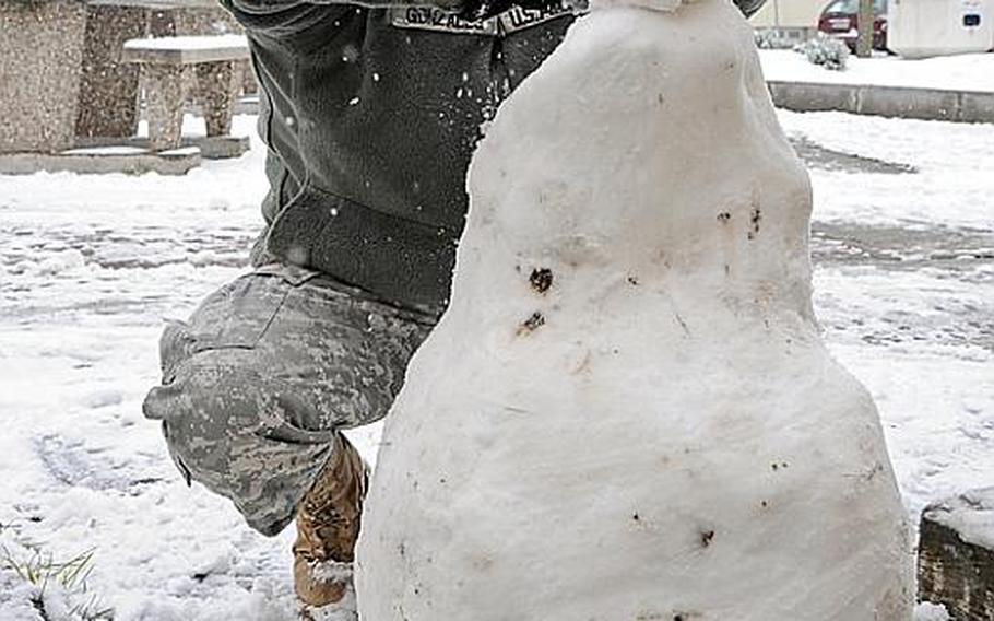 Spc. Michael Gonzales, with the 39th Transportation Battalion and from San Antonio, builds a snowman outside the Kleber Kaserne dining facility in Kaiserslautern, Germany, on Monday afternoon. Many American military communities across Germany received their first heavy snowfall of the season.