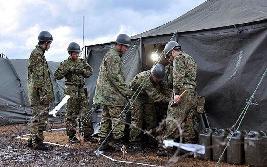 Members of the Japan Ground Self-Defense Force work on a tent at a bivouac site on Misawa Air Base, Japan, on Friday, the first day of Keen Sword 2011. The exercise includes more than 44,000 U.S. and Japanese troops across the country. Misawa's portion of the exercise will focus on a 'guard and protect' mission of the base.