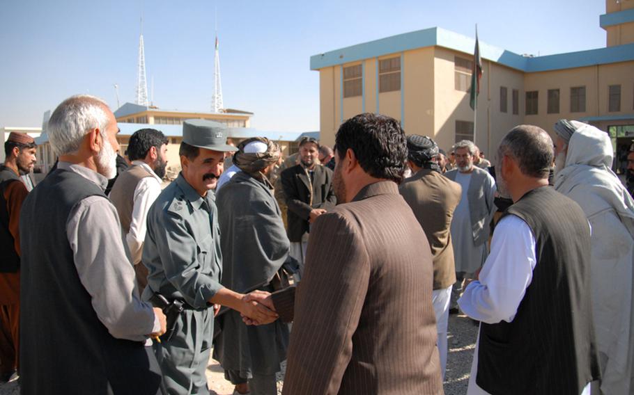 Col. Shir Shah, the Dand district chief of police, greets a member of the Kandahar governor's staff before a district government meeting last month. Shir Shah's authority is undermined by prominent power brokers who have behind-the-scenes control over the majority of his police force.