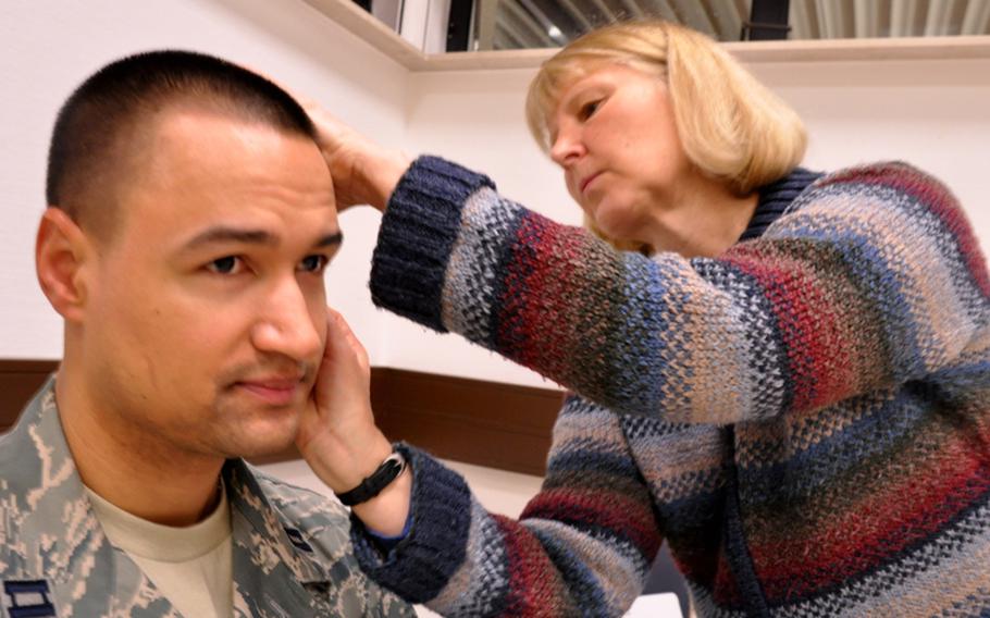 Army Lt. Col. Nancy Steele, head of nursing research for European Regional Medical Command, inserts several tiny needles in the ears of Air Force Capt. Maurice Jackson, of the 86th Contingency Aeromedical Staging Facility. Garner was practicing on Jackson in preparation for a study, where she will be one of two nurses who perform "battlefield acupuncture" on patients prior to an air evacuation flight to the States. This is the first time that nurses have been allowed to perform the acupuncture procedure, she said.
Seth Robbins/Stars and Stripes