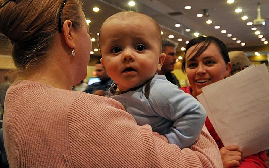 Ronin Barber, six months, waits his turn in a pre-processing line Saturday at Misawa Air Base, Japan, for family members wishing to leave Japan under a 'voluntary departure' program following a devastating earthquake and tsunamis that hit Japan on March 11. Ronin is being held by family friend Christy Starns, as his mom, Rachel, talks in the background.