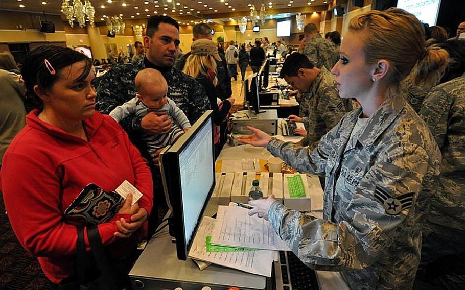 Petty Officer 1st Class Richard Barber, his wife, Rachel, and 6-month-old son, Ronin, listen Saturday as Senior Airman Shannon Valenzuela explains how they'll be contacted when it's time for Barber's family to leave Misawa Air Base, Japan, under a voluntary departure program