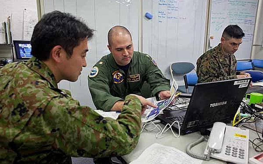 Lt. Cmdr. Barnet Harris, center, assigned to the Bilateral Crisis Action Team at Camp Sendai, Japan, works with Japan Self Defense Force troops to coordinate joint U.S. and Japanese relief efforts.