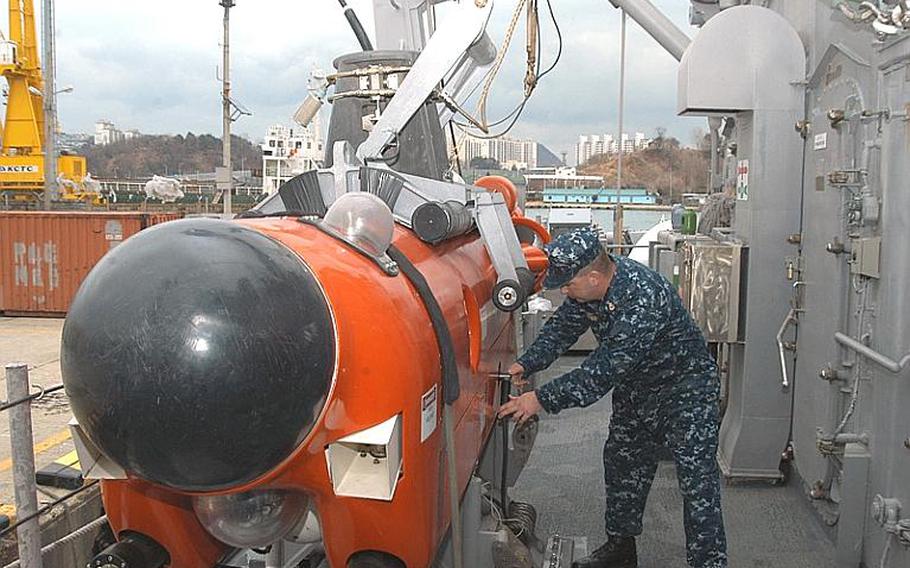 USS Avenger Mineman Chief Petty Officer David Fuhrman points out some of the features on one of the ship&#39;s mine neutralization vehicles. The remote-controlled vehicles are equipped with sonar, two cameras and cutter arms that can cut a chain or cable holding a mine underwater. The vehicles can also deliver "bomblets" to disable sea mines.