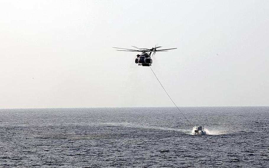 An MH-53E Sea Dragon helicopter from Helicopter Mine Countermeasures Squadron 15 drags a MK-105 Mod 4 Sled, used to help locate and detonate underwater magnetic mines in the Persian Gulf.