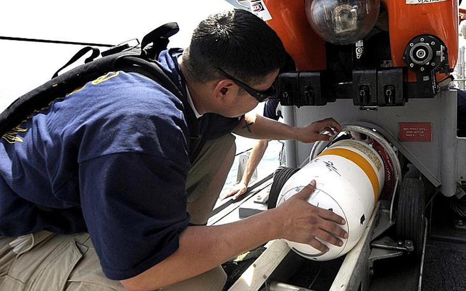 Chief Mineman Edward Sandoval, assigned to Mine Warfare Crew Persistent, loads a countermeasure bomb in a mine neutralization vehicle to prepare for a search of a training mine shape. 