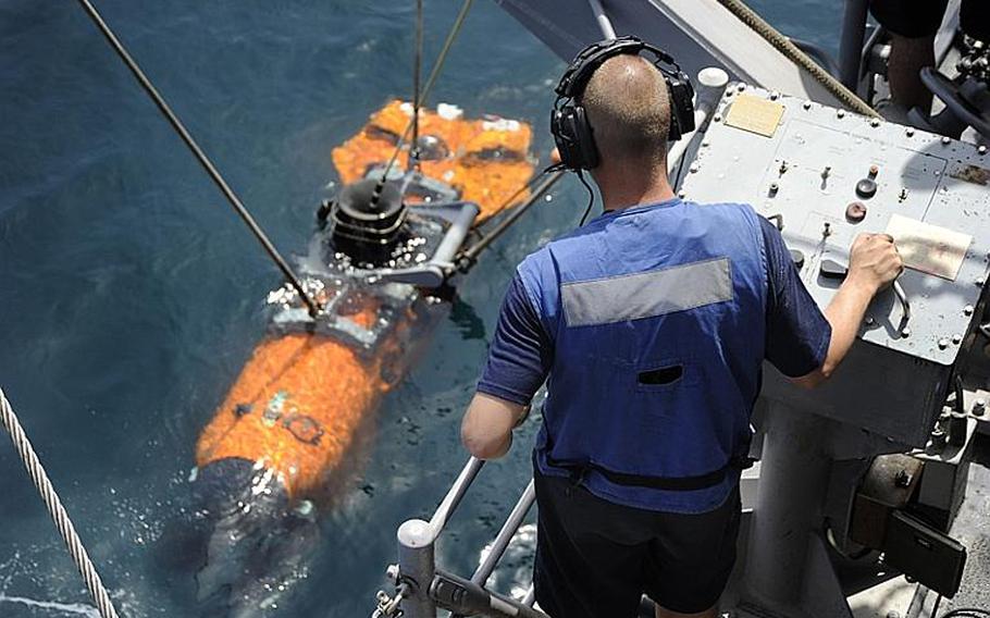 Petty Officer 3rd Class Joshua Pallent, from Mine Warfare Crew Persistent, lowers a mine neutralization vehicle into the central Arabian Gulf to search for a training mine shape. 