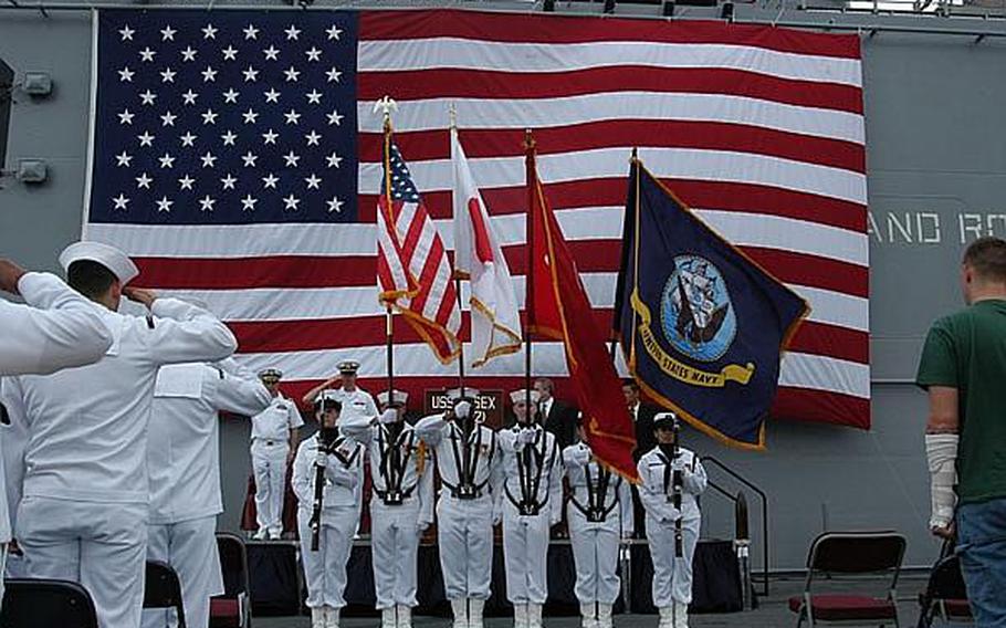 Those in attendance at Friday's ceremony stand or salute the colors, presented by the USS Essex's color guard.