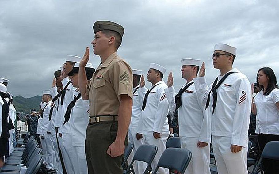 Marine Cpl. Antonino Mautino, from Marine Corps Air Station Iwakuni, left, and Seaman Tian Tan of the USS Denver, right, take the Oath of Allegiance on Friday aboard the USS Essex.