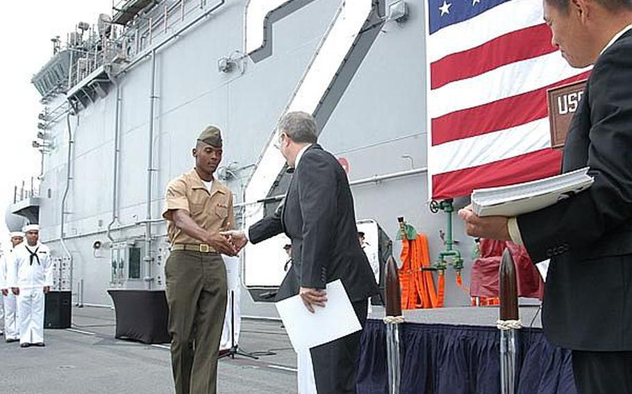Marine Lance Cpl. Mario Pierre Pierre, from Marine Corps Air Station Iwakuni, is greeted by Essex commander Capt. David Fluker, and Kenneth Sherman, an official from the U.S. Citizenship and Immigration Services, after becoming a U.S. citizen during a ceremony aboard the USS Essex Friday.