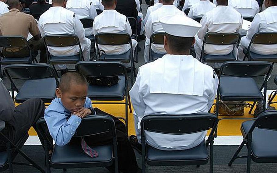 Trinol Von Mondaya, 7, left, waits patiently aboard the USS Essex on Friday to recite the Oath of Allegiance and become a U.S. citizen. Next to him is his father, USS Germantown Petty Officer 1st Class Trinol Mondaya.