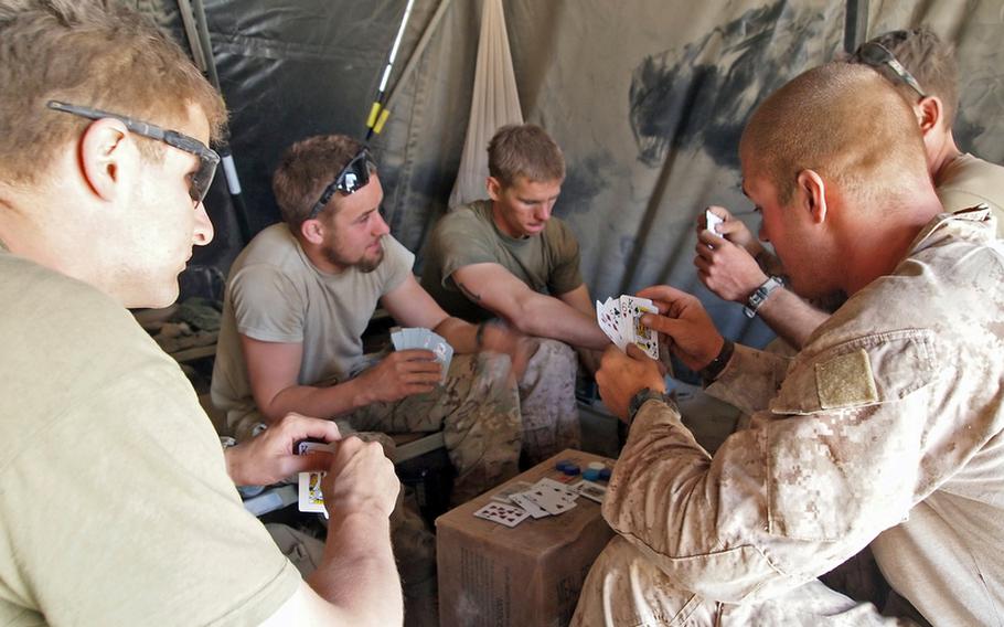 Sgt. Peter Melcon, left, who was injured by enemy indirect fire while building Patrol Base Salaam Bazaar, plays cards with fellow Marines after returning to duty.