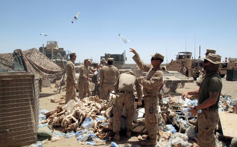 Marines toss bottles of water dropped off by a supply convoy into empty Hesco barriers used to store supplies at Patrol Base Salaam Bazaar. Marines established the base May 16 by building a perimeter of Hesco barriers, wire and fabric baskets typically filled with rock and sand. By Thursday they had added a bunker and only the barest of amenities, including two outhouse stalls, tubes to urinate into, a space for showering and few tents.