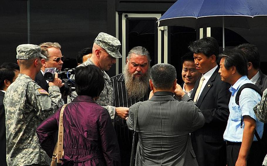 Steve House, center, studies a map of Camp Carroll&#39;s helipad area and discusses where he believes he buried barrels of Agent Orange in 1978. Surrounding him are South Korean lawmakers and members of a joint U.S.-South Korean task force who are investigating his claims. Standing beside House is Col. Joseph Birchmeier, a U.S. Forces Korea engineer.
