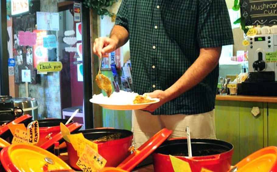 Ryan Young, an Air Force spouse, ladels curry onto his plate at a restaurant in American Village. The shopping and entertainment complex was once U.S. Army land but now is one of the biggest commercial draws in central Okinawa. The island hopes it can repeat that success when other military land is returned in the future.
