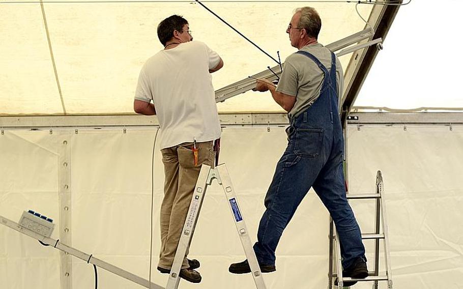 Markus Hunsinger (left) and Ferdinand Eisenzimmer, electricians with ITT Federal Services, install lighting inside the temporary tent that will serve as the shoppette on Kleber Kaserne after a fire destroyed the Kleber shoppette late Sunday night.
Joshua L. DeMotts/Stars and Stripes