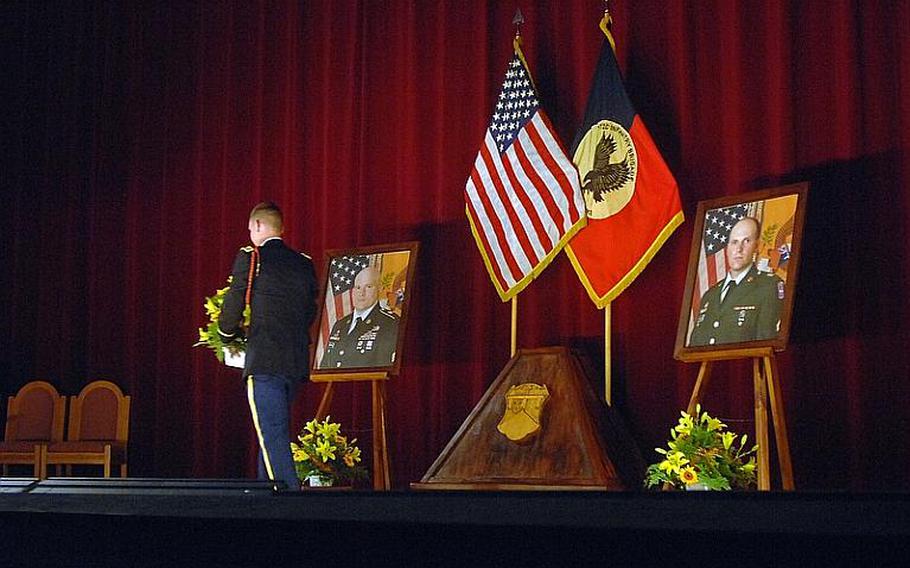 A soldier walks past the portrait of Sgt. Matthew Harmon following Wednesday's memorial ceremony for Harmon and Spc. Joseph VanDreumel, pictured at right. Harmon and VanDreumel, mechanics with Company A, 1st Battalion, 2nd Regiment, Task Force 3-66, were killed by a roadside explosion on Aug. 14 in eastern Afghanistan.